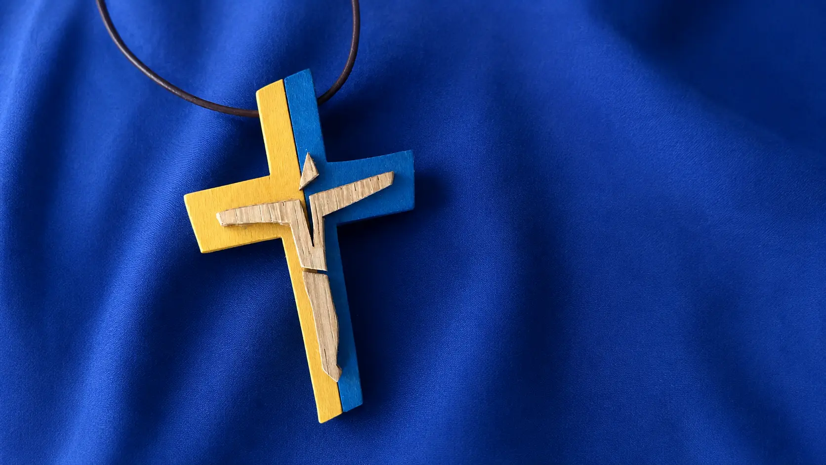 Holzkreuz der Schulseelsorge auf blauem Stoff